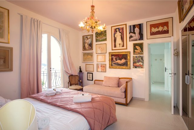 Schlafzimmer im Ch&acirc;teau de l&rsquo;Anglais mit Doppelbett, Sofa, Kronleuchter und Gem&auml;lden, Bogenfenster zum Balkon