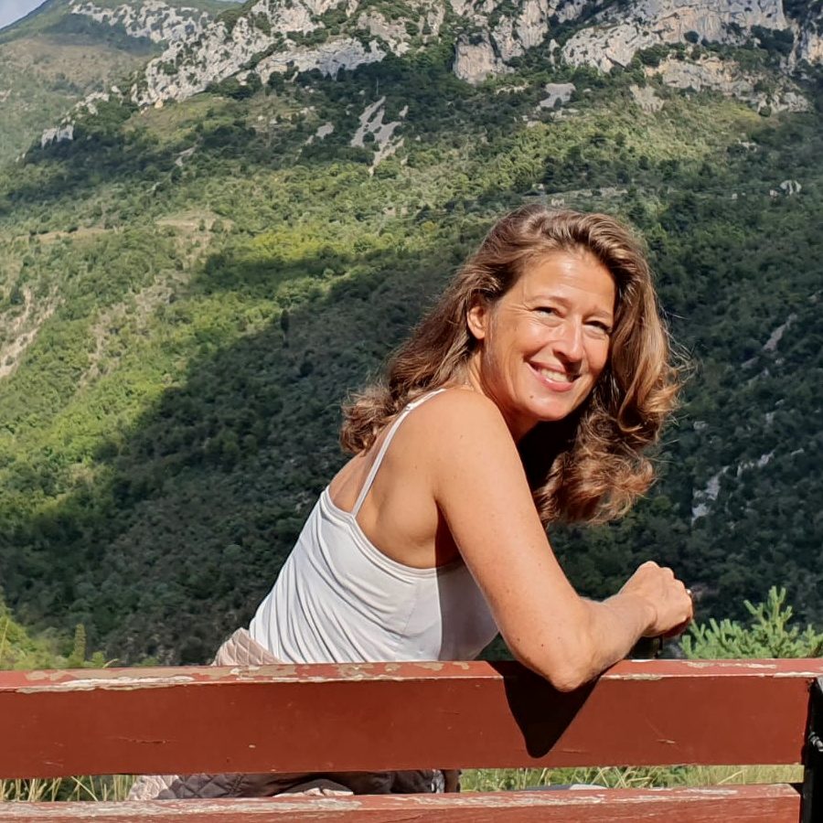 Gesa Kaehlbrandt assise sur un banc au-dessus de la vall&eacute;e, les pentes bois&eacute;es des baous derri&egrave;re elle
