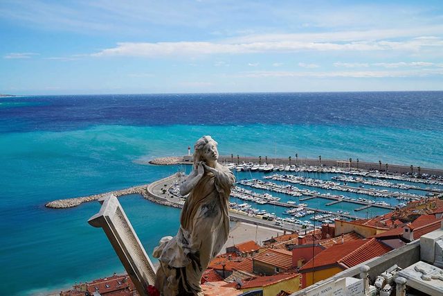 Blick &uuml;ber den Hafen von Menton auf das Meer, im Vordergrund eine Steinfigur