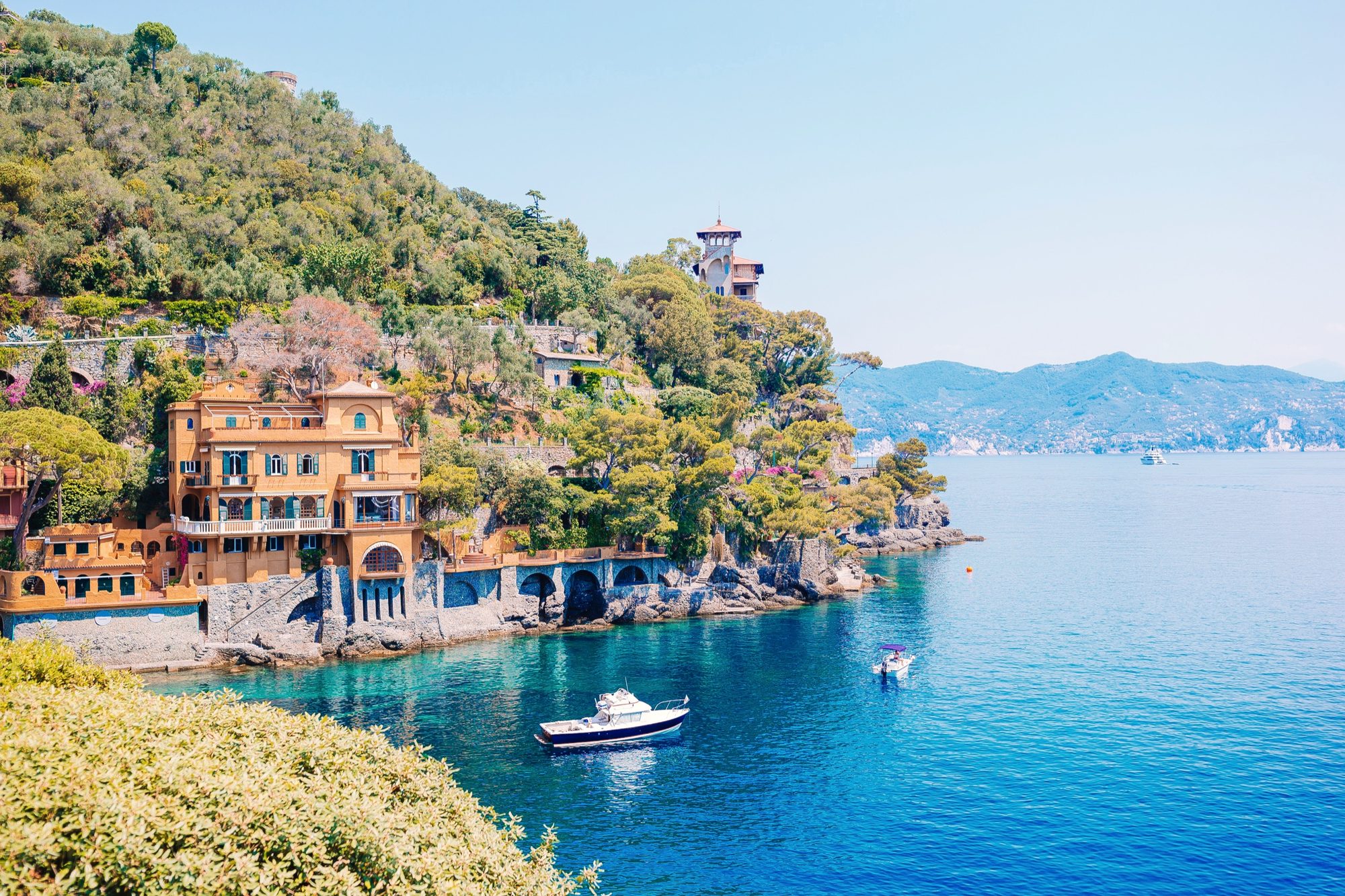 Weite Bucht an der Côte d’Azur mit türkisem Wasser, bewaldetem Hang und Booten vor Anker