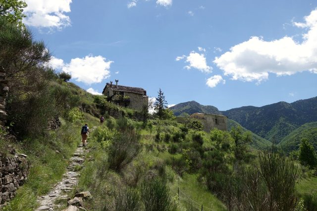 Wanderin auf einem Steinpfad zu einer Kapelle am Hang